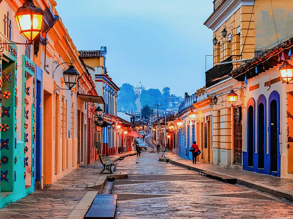 A colonial street in San Cristóbal de las Casas, Chiapas, at dusk with the lamps lit